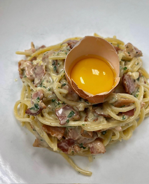 Plated Spaghetti alla Carbonara with guanciale, egg yolk, and pecorino